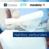 Hand mit OP-Handschuh schneidet Gaze-Verband